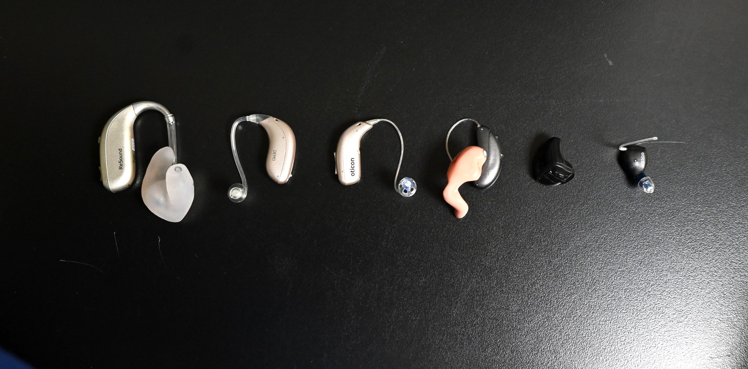 A range of hearing aid styles lined up, from behind the ear devices to nearly invisible in the canal models