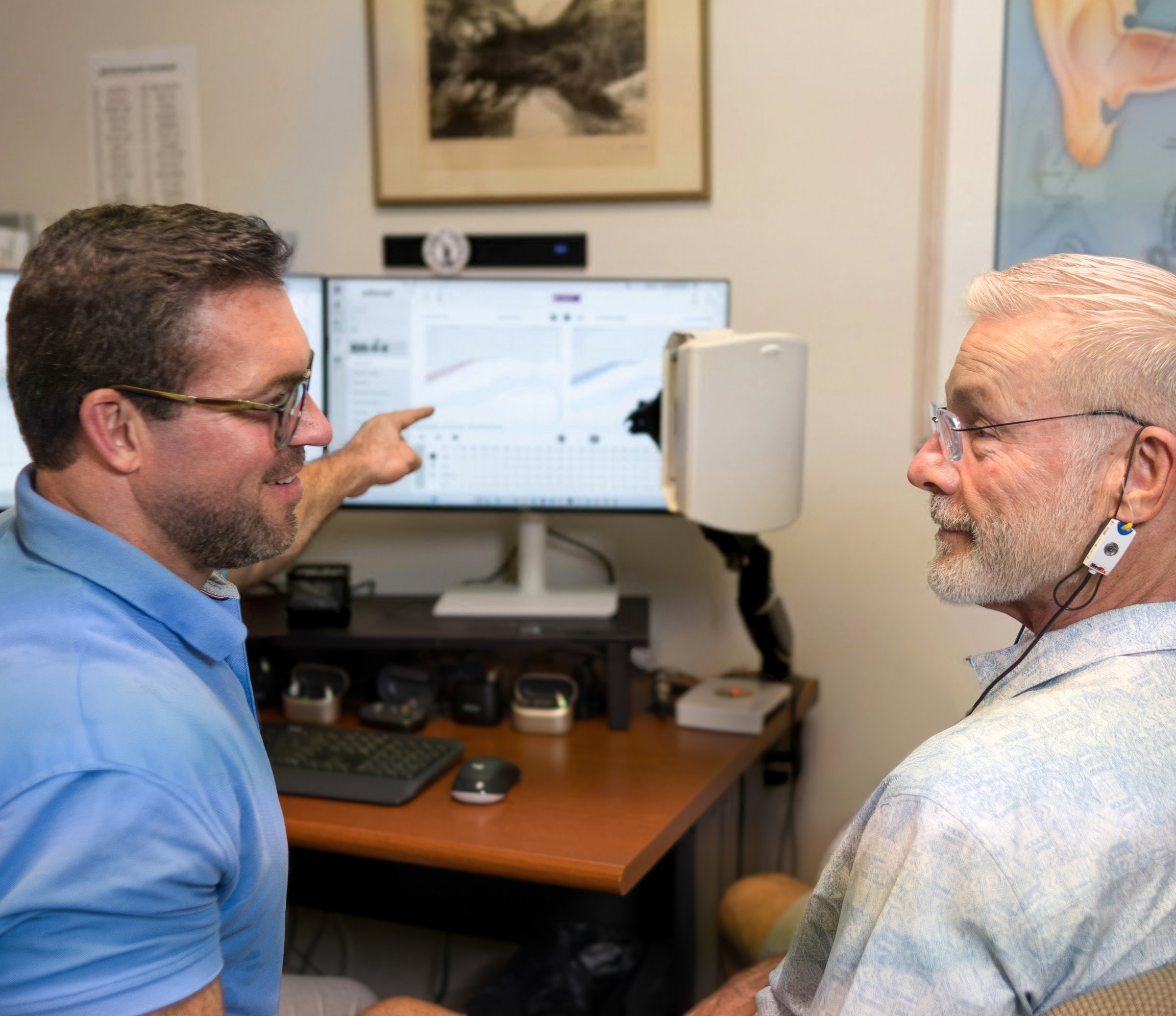 Andy Schirmer holding the Real Ear Measurement speaker at a patient's ear during a verified fitting